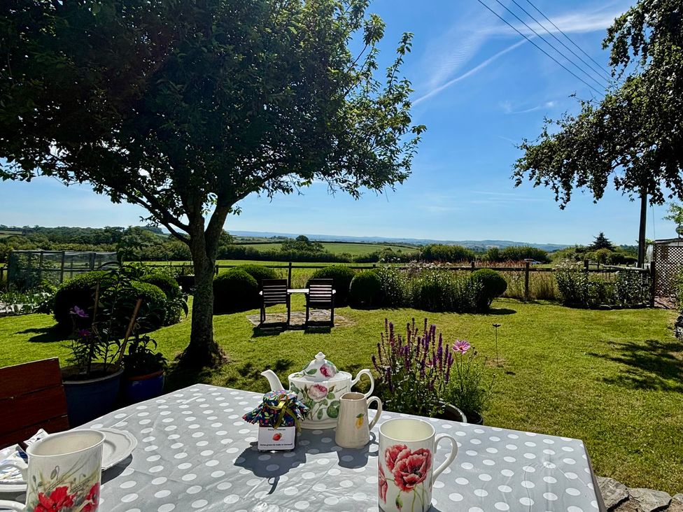 A garden with a table and chairs overlooking fields at Cider Cottage near Launceston