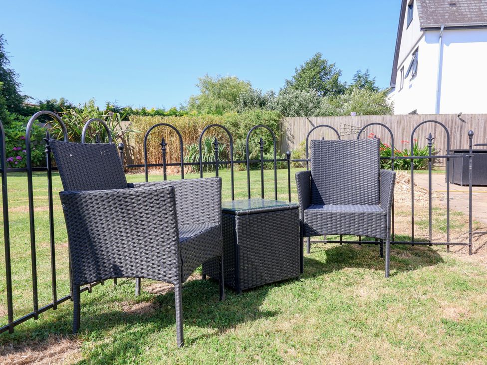 A garden with wicker chairs and table at Coach House Highampton near Black Torrington