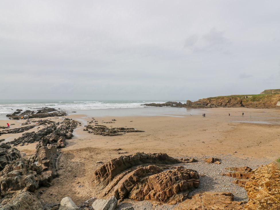A beach with sand and rocks and people at the shoreline near Coach House in Highampton near Black Torrington