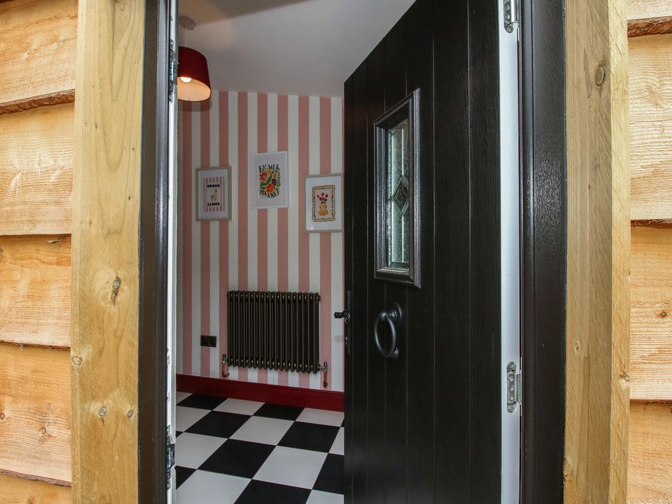An entrance with a black door and patterned wall at The Dinky Dairy in Treflach near Trefonen