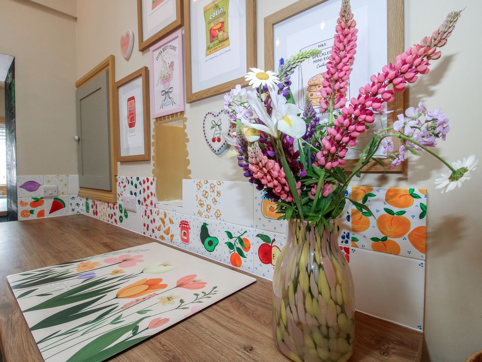 A kitchen with a vase of flowers and wall art at The Dinky Dairy Treflach near Trefonen