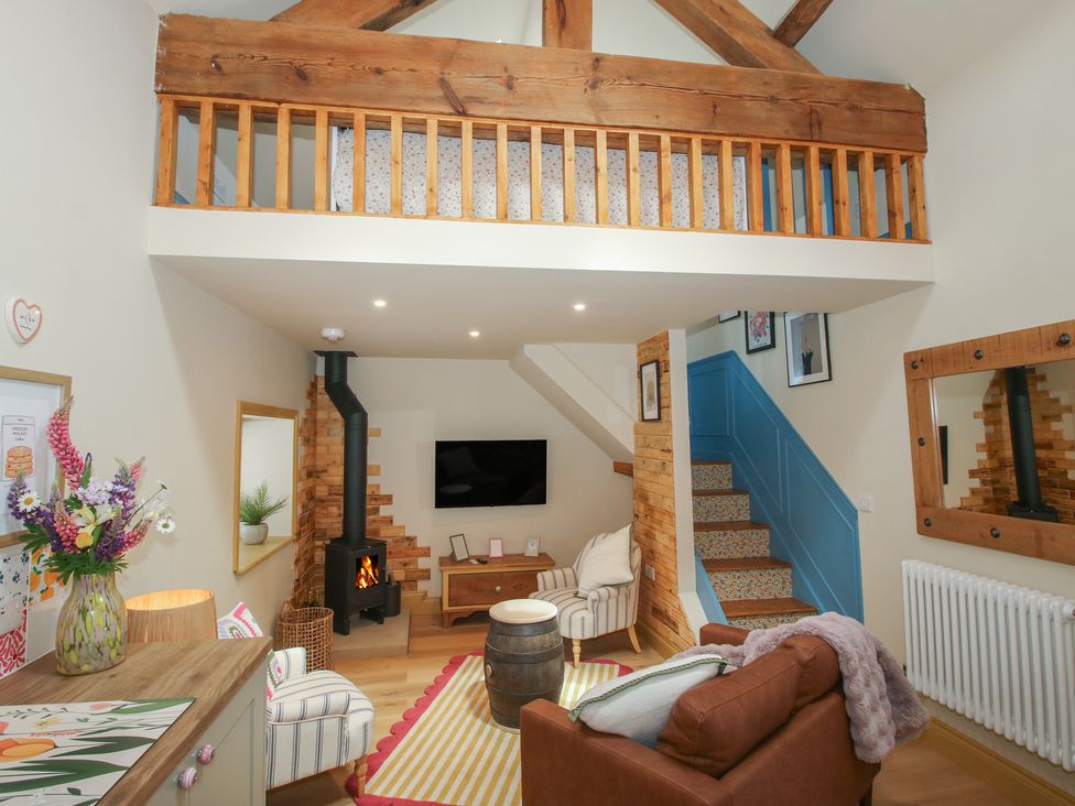 A living room with a sofa, television and stairs at The Dinky Dairy in Treflach near Trefonen