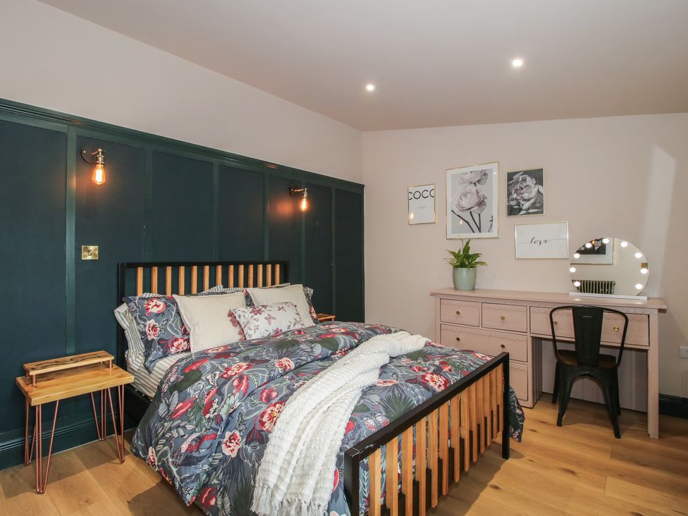 A bedroom with a bed, dresser, and wall art at The Dinky Dairy in Treflach near Trefonen