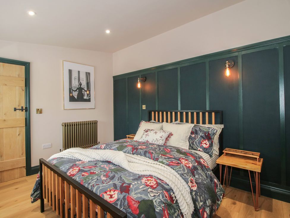 A bedroom with a bed and nightstand at The Dinky Dairy in Treflach near Trefonen