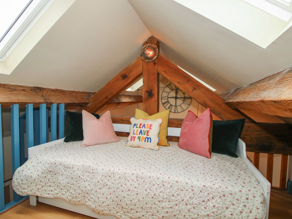 A loft area with a daybed and pillows at The Dinky Dairy Treflach near Trefonen