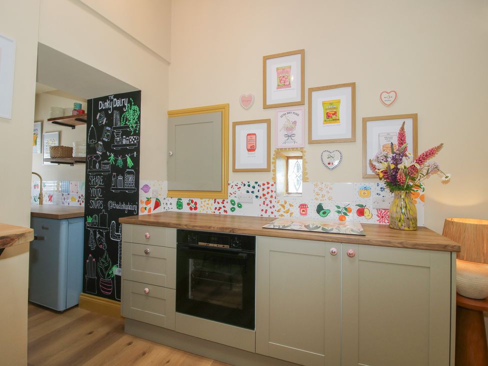 A kitchen with cabinets and a blackboard wall at The Dinky Dairy Treflach near Trefonen