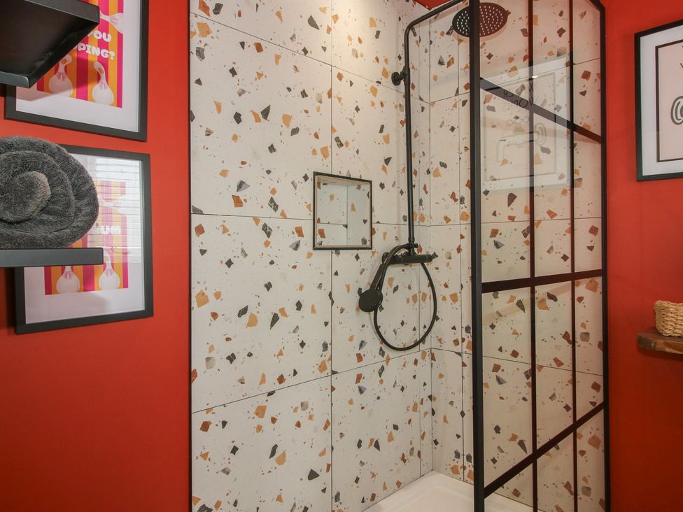 A shower area with tiled walls and a towel at The Dinky Dairy in Treflach near Trefonen