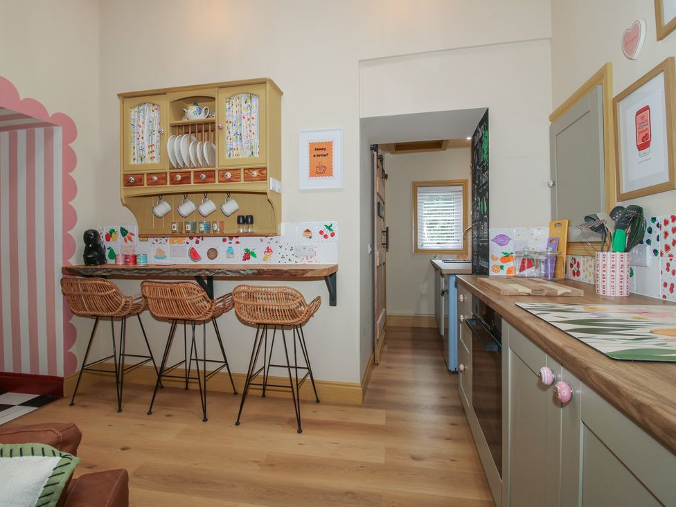 A kitchen with bar stools and shelves at The Dinky Dairy Treflach near Trefonen