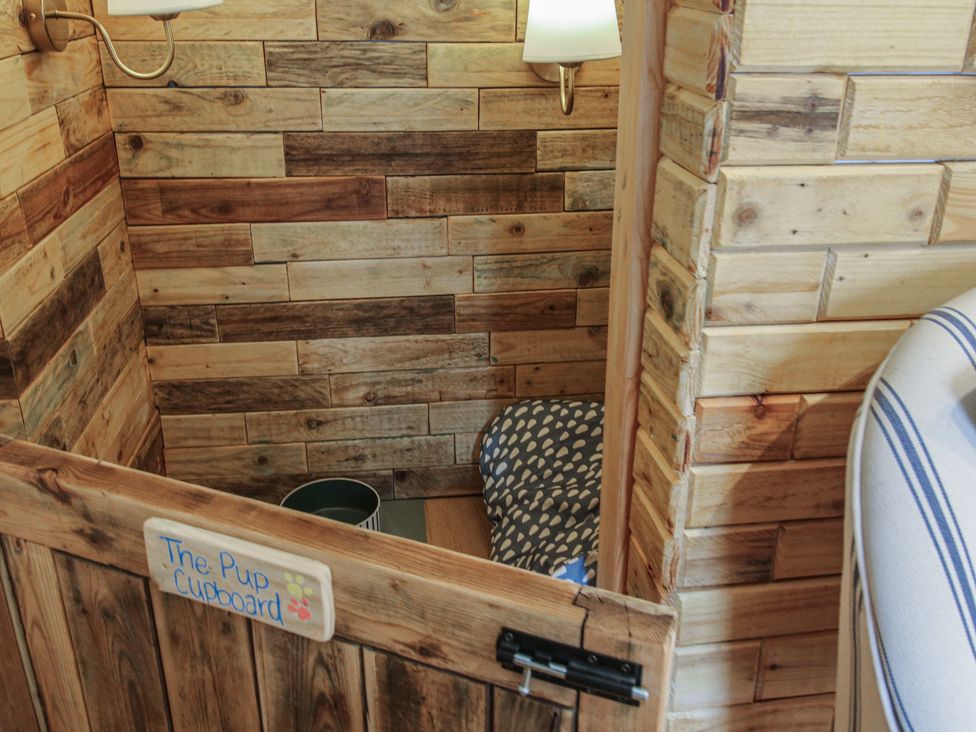 A pet cupboard with wooden walls and a dog bed at The Dinky Dairy in Treflach near Trefonen