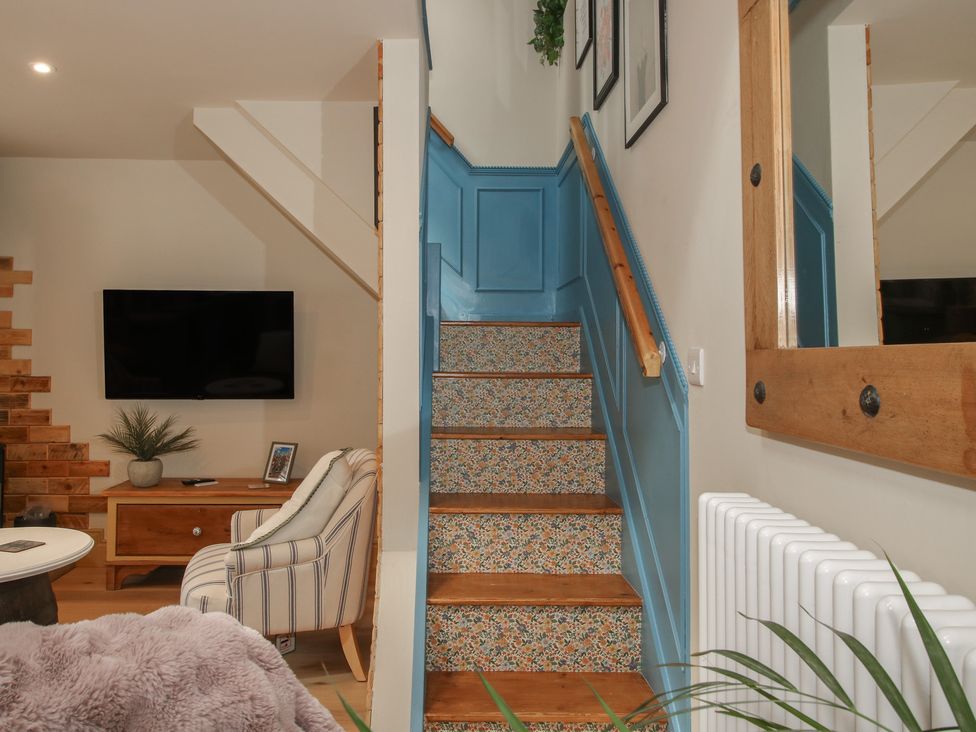 A living room with a staircase and television at The Dinky Dairy in Treflach near Trefonen