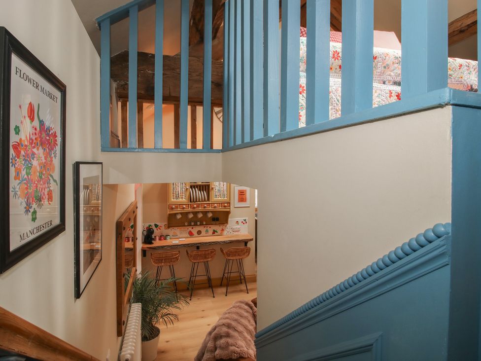 A staircase leading to a kitchen area with bar stools at The Dinky Dairy Treflach near Trefonen