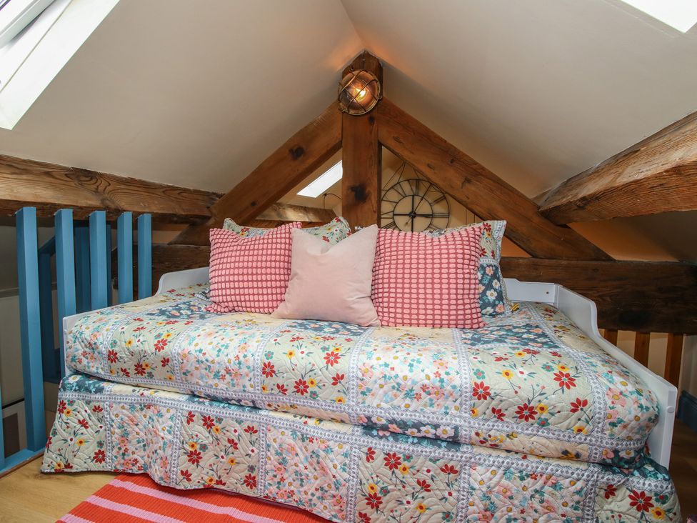 A loft with a daybed and pillows at The Dinky Dairy in Treflach near Trefonen