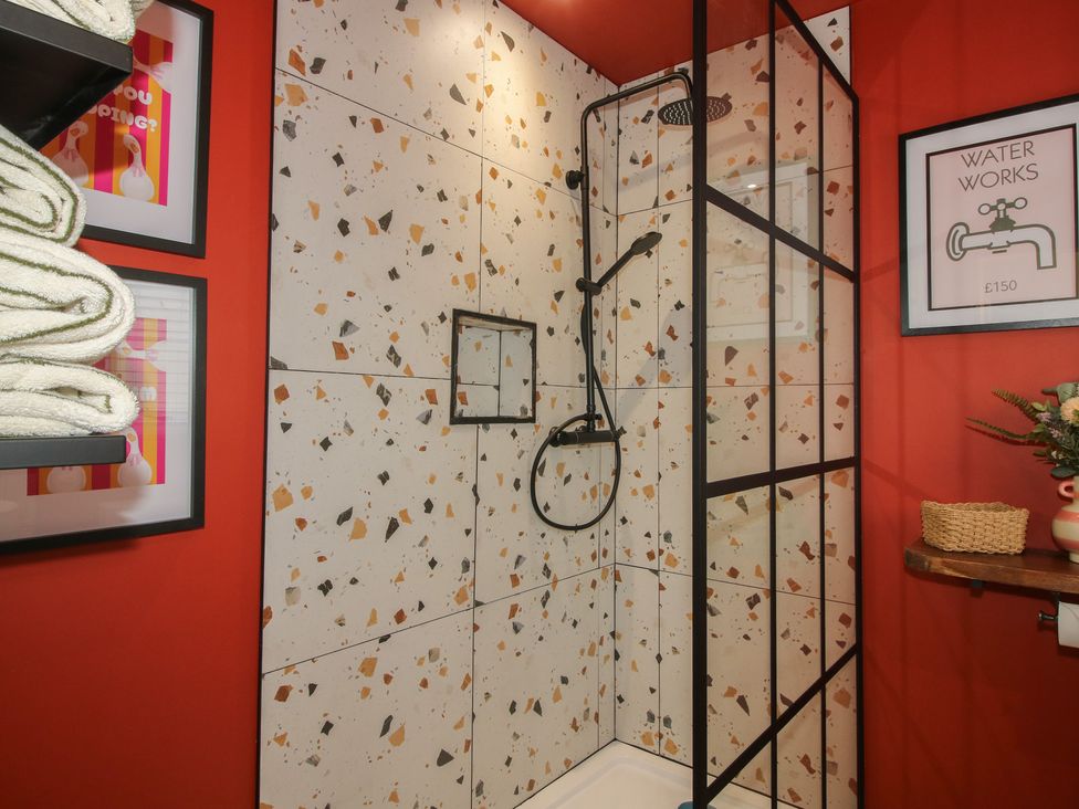 A shower area with wall tiles and towels at The Dinky Dairy in Treflach near Trefonen