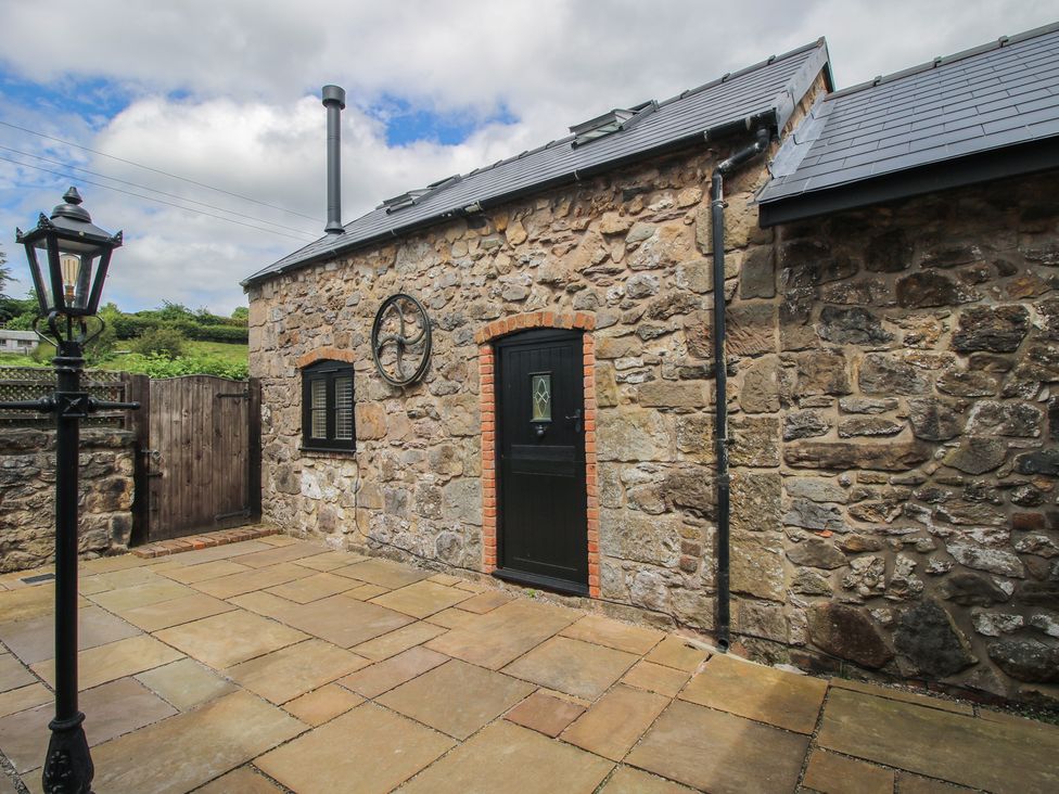 An outdoor area with a stone wall and a black door at The Dinky Dairy in Treflach near Trefonen