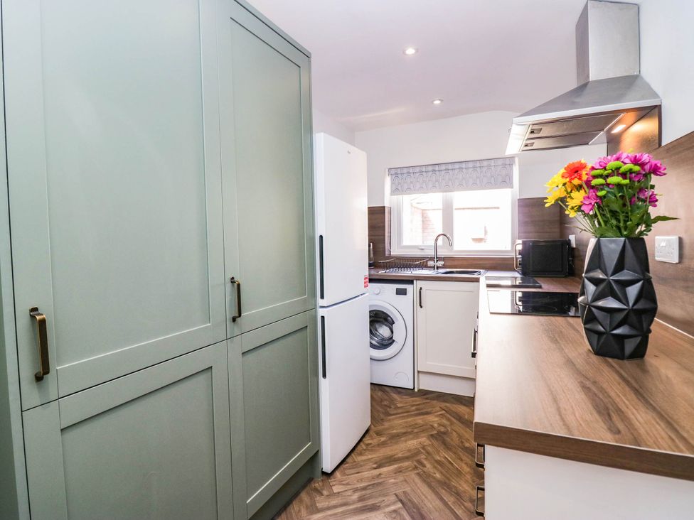 A kitchen with cabinets, refrigerator, washing machine and sink at 24 Harrington Road Workington