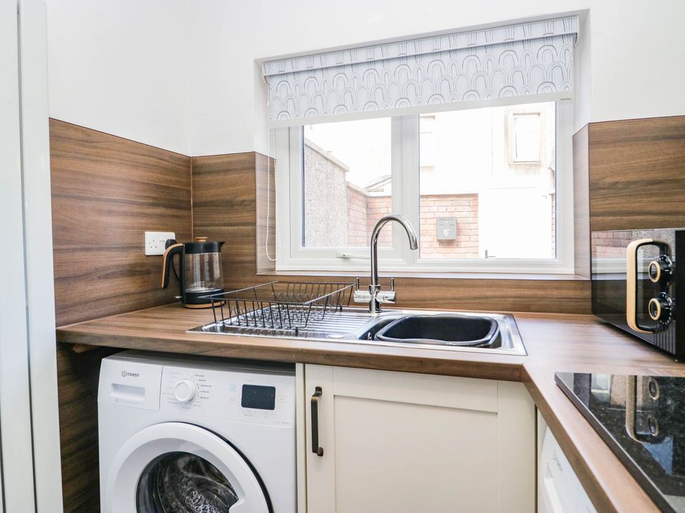 A kitchen with a sink and washing machine at 24 Harrington Road Workington