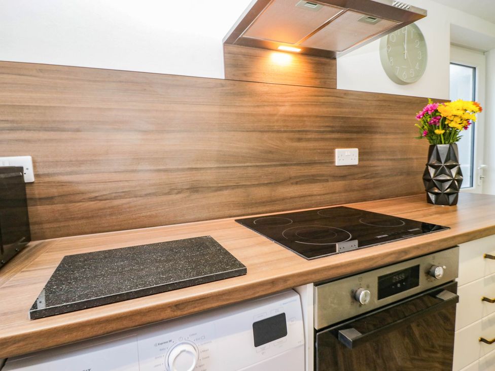 A kitchen with an induction hob, oven, and washing machine at 24 Harrington Road Workington