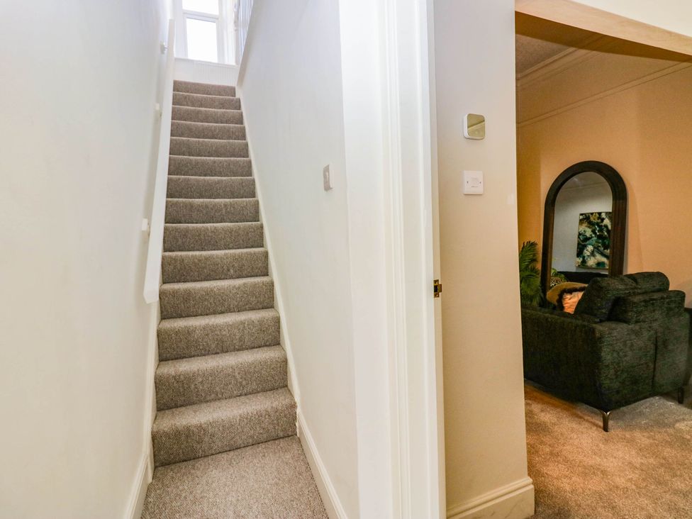 A hallway with stairs and a view of the living room at 24 Harrington Road Workington