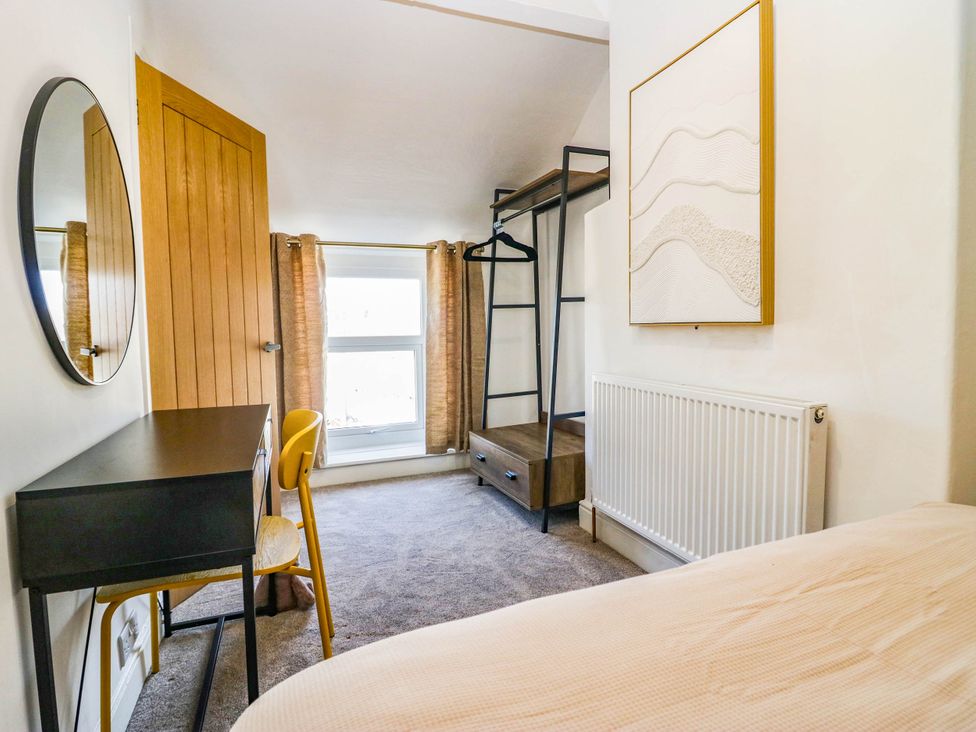 A bedroom with a desk, chair, and clothes rack at 24 Harrington Road, Workington