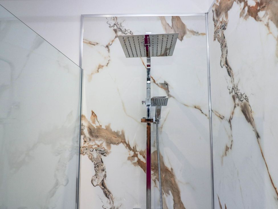 A shower with a marble wall and glass enclosure at 24 Harrington Road Workington