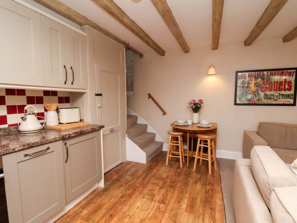A kitchen with a dining table and staircase at Wick Cottage in Whitby