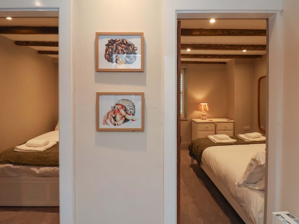 A bedroom with two beds and artwork on the wall at Wick Cottage in Whitby