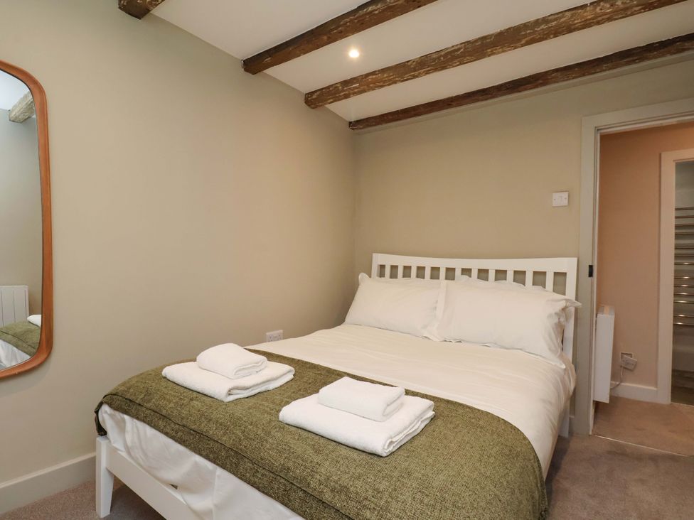 A bedroom with a bed and mirror at Wick Cottage in Whitby