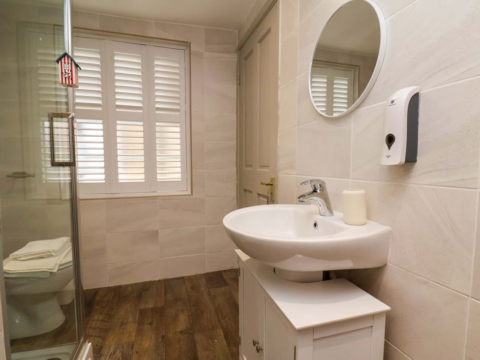 A bathroom featuring a shower, toilet, and sink at Wick Cottage in Whitby