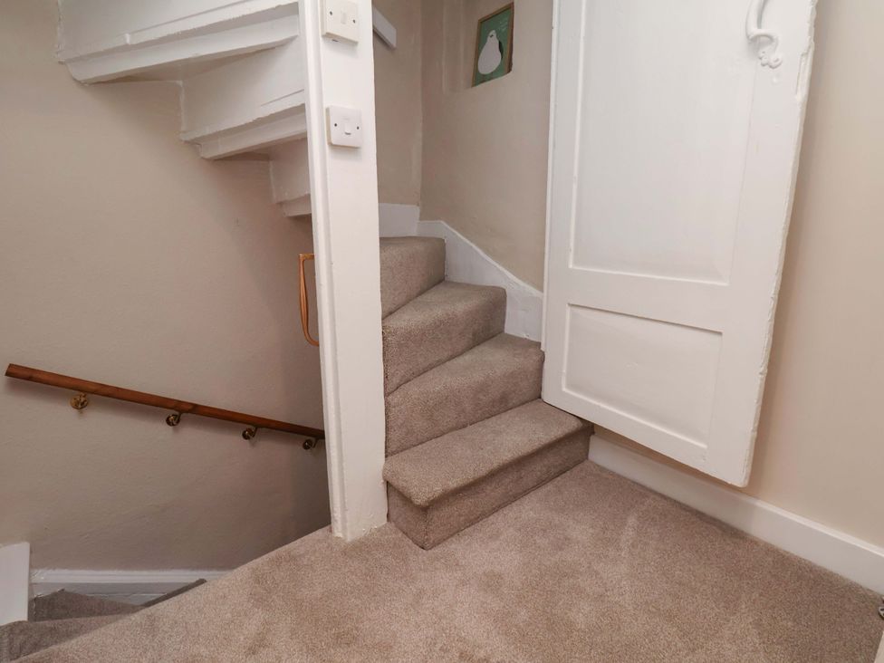A staircase with a door and handrail at Wick Cottage in Whitby