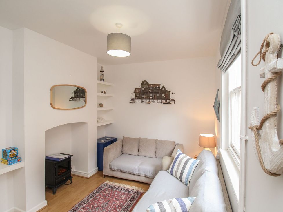 A living room with a sofa, lamp, and mirror at Pixie Cottage in Weymouth