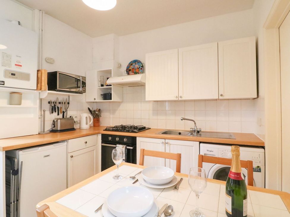 A kitchen with appliances and dining table at Pixie Cottage in Weymouth