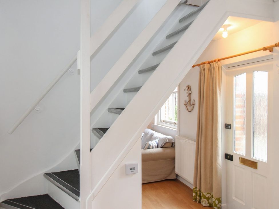 A hallway with a staircase and a front door at Pixie Cottage in Weymouth
