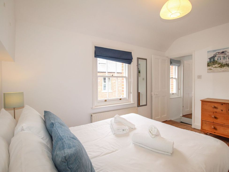 A bedroom with a bed and a chest of drawers at Pixie Cottage in Weymouth