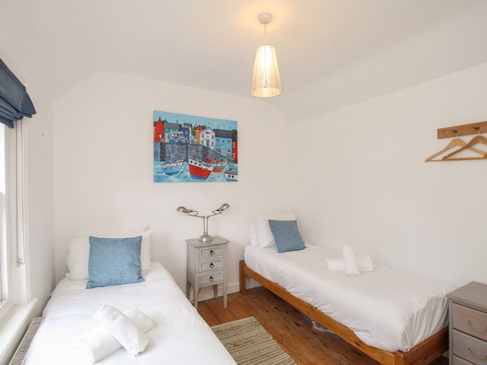 A bedroom with two beds and a nightstand at Pixie Cottage Weymouth