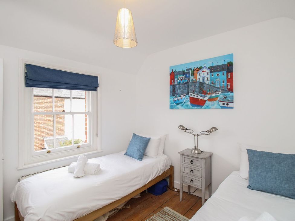 A bedroom with two beds and a painting on the wall at Pixie Cottage in Weymouth