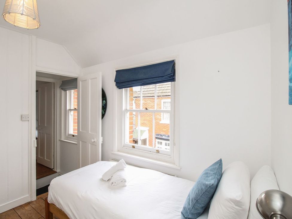 A bedroom with a bed and windows at Pixie Cottage in Weymouth