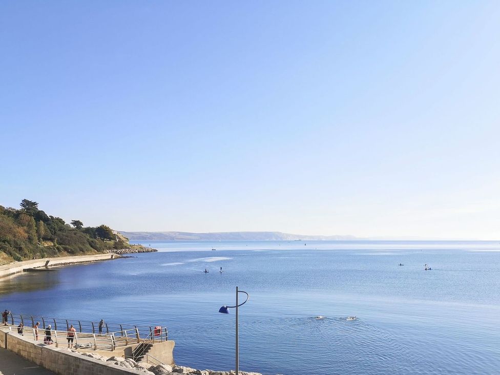 A coastal view with a walkway and people at Pixie Cottage in Weymouth