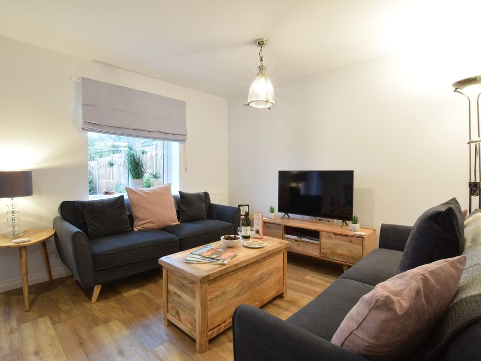 A living room with a sofa, coffee table, and a television at Lapwings, Aldeburgh