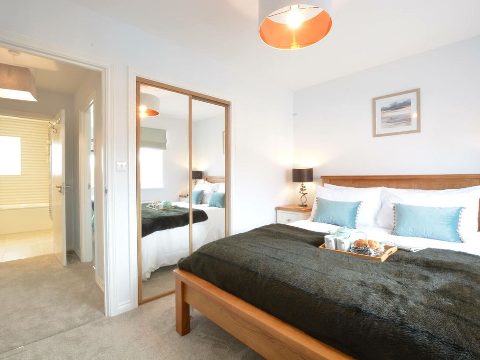 A bedroom with a bed and side table at Lapwings, Aldeburgh
