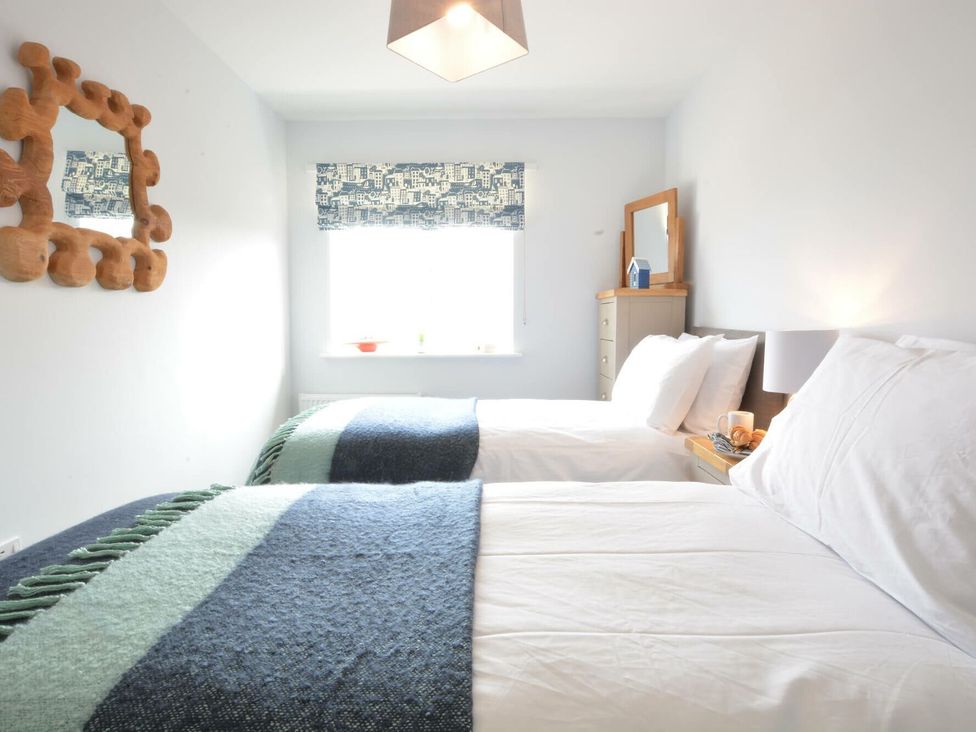 A bedroom with two beds and a mirror at Lapwings, Aldeburgh