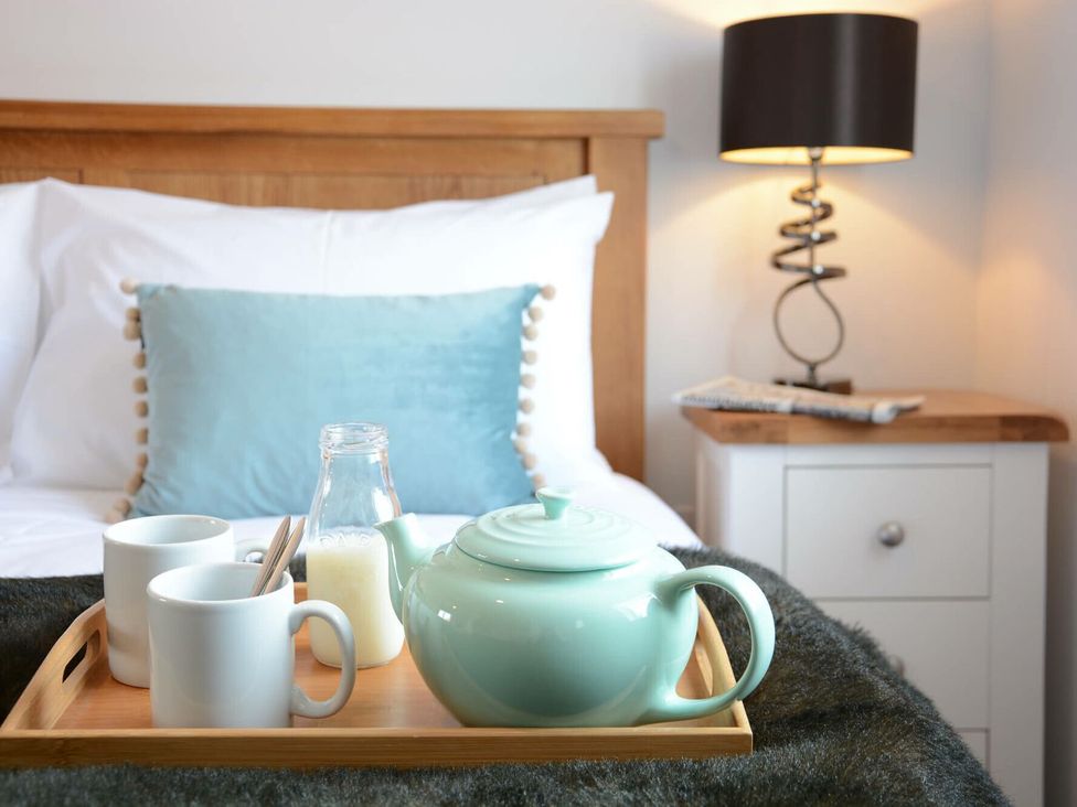 A bedside tray with a teapot, mugs, and milk bottle at Lapwings, Aldeburgh