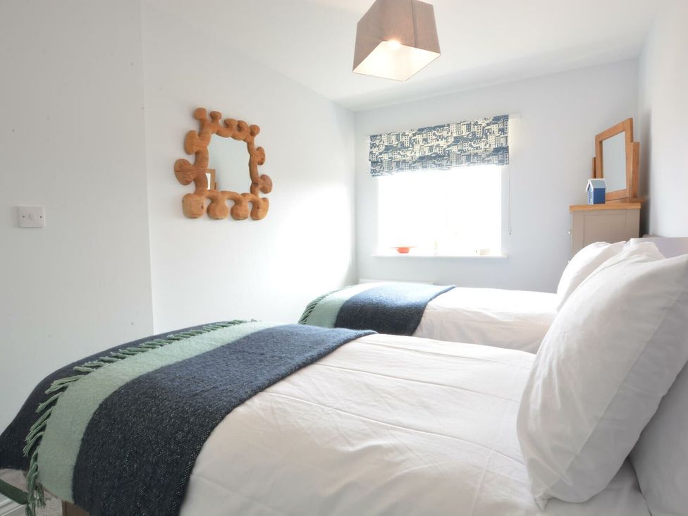 A bedroom with two beds and a mirror at Lapwings, Aldeburgh
