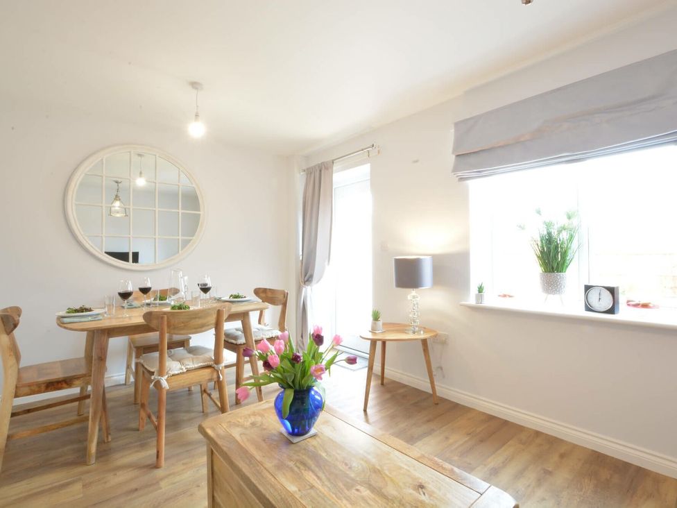 A dining room with a table set and a lamp at Lapwings, Aldeburgh