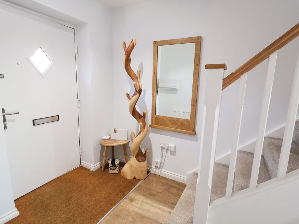 A hallway with a door, mirror, and decorative sculpture at Lapwings, Aldeburgh