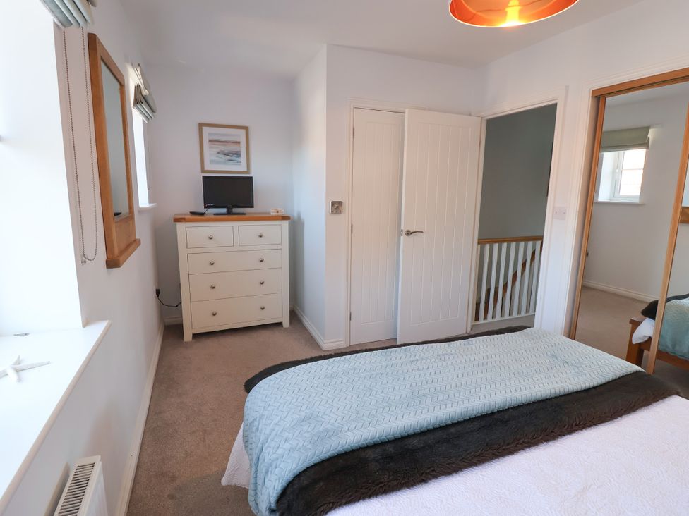 A bedroom with a bed and dresser at Lapwings, Aldeburgh