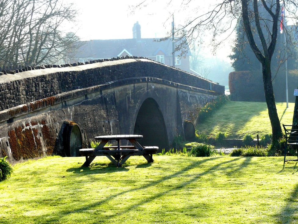 A bridge with a picnic table and grass in a park at Whitefield Cottage Barnstaple