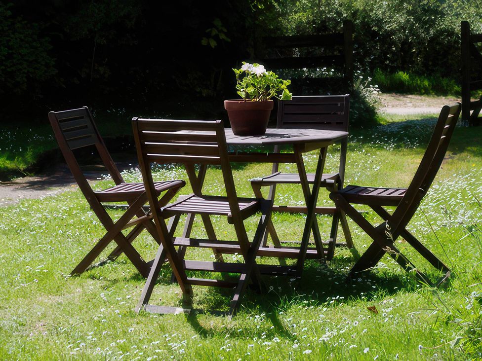 A table and chairs with a flower pot at Whitefield Cottage in Brayford near North Molton