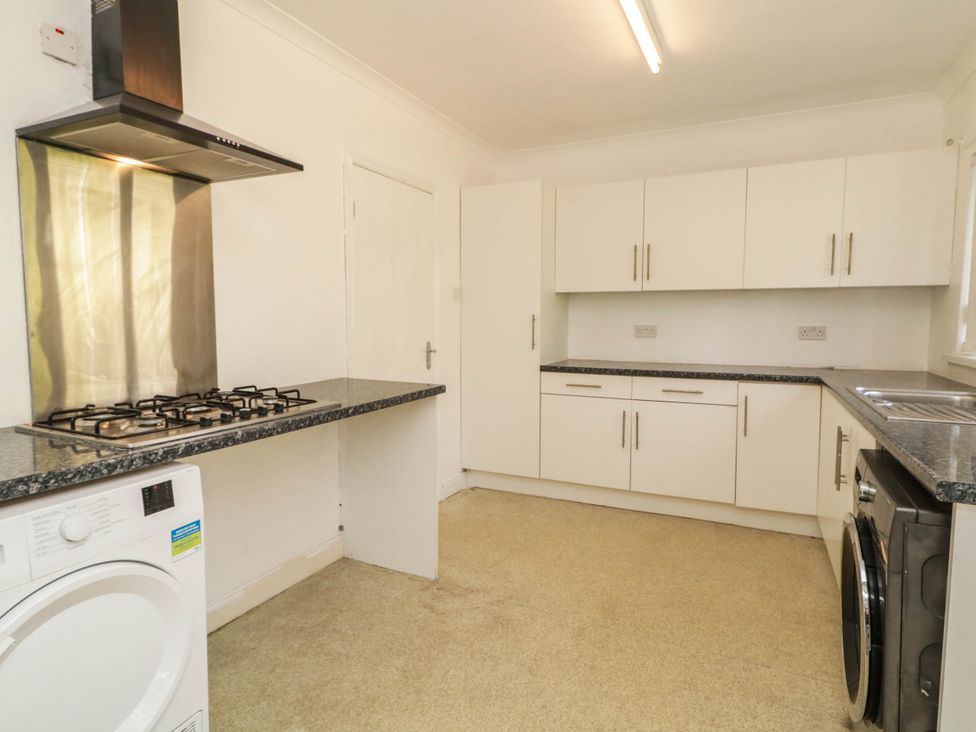 A kitchen with a gas stove, washing machine, and countertop at 59 Nursery Avenue Coleraine