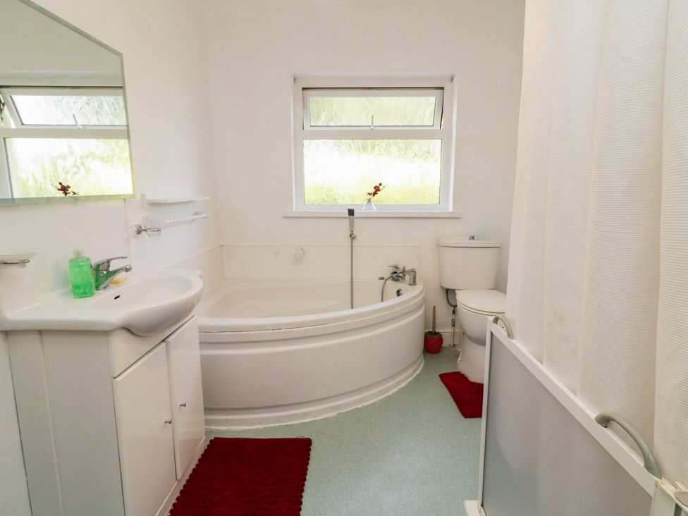 A bathroom with a bathtub, toilet, sink, and window at 59 Nursery Avenue, Coleraine