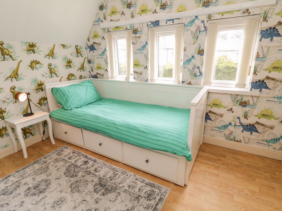 A bedroom with a bed and window with dinosaur wallpaper at 59 Nursery Avenue in Coleraine